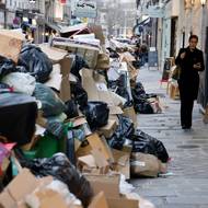 Žena prochází kolem pytlů s odpadky, které se na pařížských ulicích hromadí od doby, kdy popeláři vstoupili do stávky. Foceno 20. března.