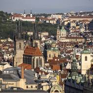 Stověžatá Praha, snímku dominuje Týnský chrám, v pozadí u petřínských sadů bíle září Strahovský klášter.