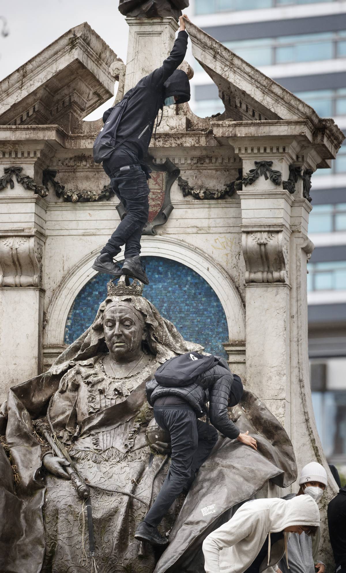 Demonstrace, které začaly minulý týden ve Spojených státech kvůli smrti černocha při zatýkání bělošským policistou se přenesly také do Velké Británie. Demonstrující na snímku šplhají na vrchol sochy Královny Viktorie v Manchestru.