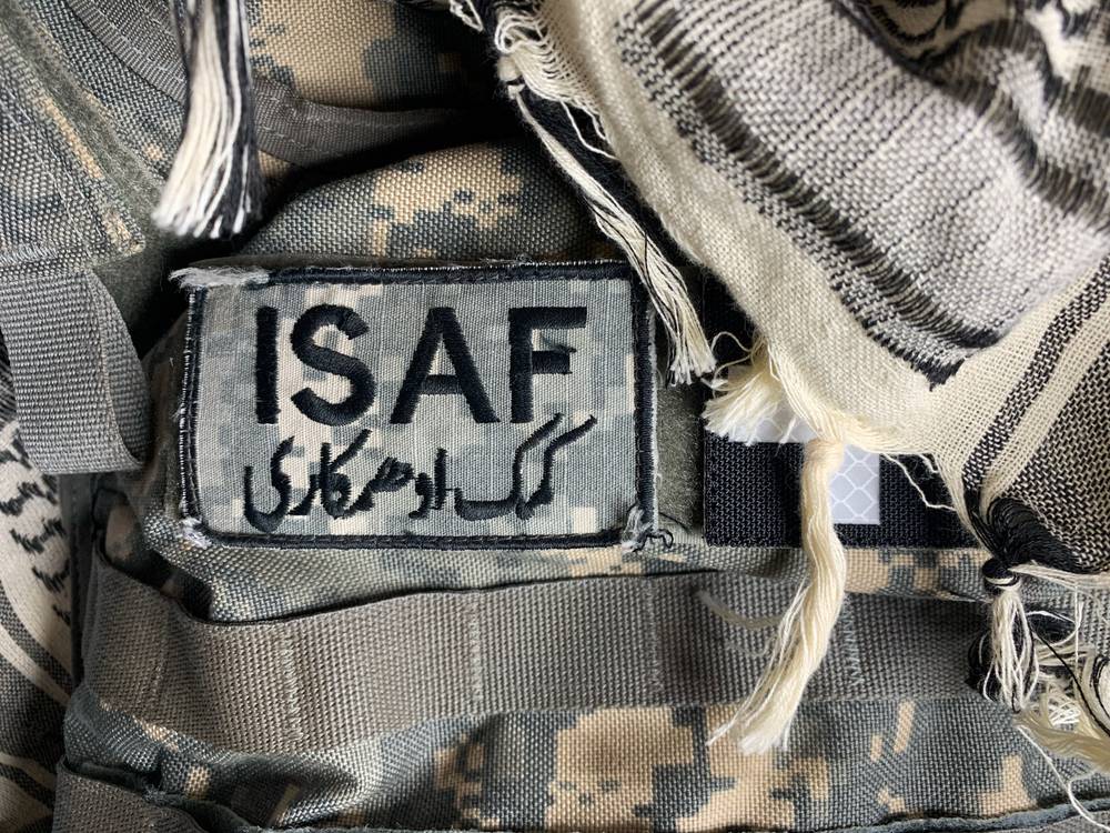 SZ / Logo Mezinárodních podpůrných bezpečnostních sil ISAF (anglicky International Security Assistance Force) s perským nápisem „pomoc a spolupráce“. Šlo o vojenskou misi NATO v Afghánistánu s původním úkolem zajistit Kábul a okolí proti bojovníkům al-Káidy a Tálibánu.