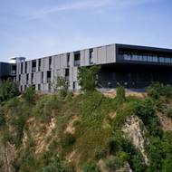 Nová část ve tvaru lichoběžníku má tmavošedou barvu a konzolovité balkony.