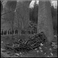 Pohled na sražený nákladní vagon, který spadl z mostu do údolí, v pozadí jeden z rychlíkových vagonů.