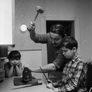 Rok 1971, dobová popiska: Otec rodiny se chystá paličkou na maso ukončit život vánočního kapra, jedno dítko drží připravený nůž, druhé v pozadí melancholicky přihlíží.