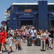 Počet návštěvníků Santorini stále roste, loni jich podle starosty Nikose Zorzose bylo asi 3,4 milionu, což vytváří tlak na zastaralou infrastrukturu a vytlačuje místní z realitního trhu. (Turisté v přístavu na Santorini, 20. července.)
