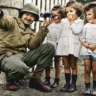Voják americké armády ukazuje v Normandii třem malým francouzským dívkám dalekohled, rok 1944.