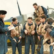 Stíhací letka 121 („Eagle Squadron“) britského královského letectva, vytvořená z amerických dobrovolníků. Zpravodajský důstojník RAF si zapisuje poznámky pilotů. Na snímku velitel Robin Powell a piloti Jim Daly, Hugh Kennard, Le Roy Skinner, Withey Martin, Fuller Patterson. 1940


