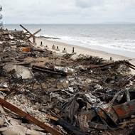 Odtahová služba si prohlíží ohořelé auto, které se pokoušela odstranit z domu na pláži zničeného požárem Palisades (Malibu, 6. března)