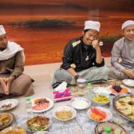 Syekh Ubaidillah Ahror v tmavě hnědém gamisu - dlouhé košili, kterou v Temboru nosí skoro všichni muži - žertuje během hostiny s návštěvníky z jižního Thajska, kde u hranic s Malajsií žije početná muslimská komunita.