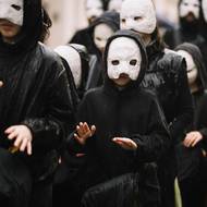 Obličeje postav v průvodu zahalují bílé masky.