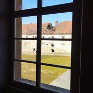 Pohled u obnoveného prvního patra hospodářského dvora na zchátralé severní křídlo.