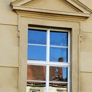 Okno na obnoveném jižním křídle hospodářského dvora, odlesk v něm ukazuje kus zchátralého severního křídla.