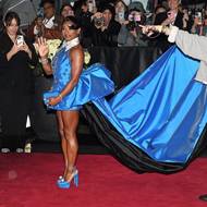 Olympijská gymnastka Simone Bilesová v modrých šatech s mimořádně dlouhou vlečkou.