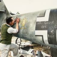 Technik odstraňuje obrázek myšky z trupu sestřeleného Messerschmittu Bf 109 německého letectva. Rok 1940. 