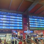 Na Hlavním nádraží v Praze zavládl zmatek. Všechny vlaky nabraly desítky minut zpoždění. Na vývěsné tabuli se podle hlášení objevují pouze ty soupravy, které skutečně pojedou. Mezitím však dispečerka hlásí odjezd i dalších vlaků, které na tabuly již nejsou uvedené. Zmatení turisté se snaží zorientovat, hlášení v angličtině ale chybí.  Místo toho halou zní jedno hlášení o zpoždění za druhým…