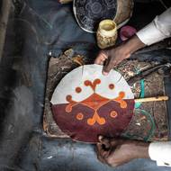 „Byla potřeba platforma věnovaná místním designérům, výrobkům a dodavatelům kůže, která by ukázala, že Nigerijci jsou schopni s vlastními zdroji vytvářet výrobky, které stojí za to koupit,“ řekl Olayebi. 

(Řemeslník připevňuje kus kůže na vějíř ve své dílně na trhu Kurmi v Kanu, 10. září.)