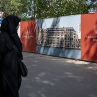 Malebné nádraží, které se tyčí přímo nad vodou, bylo slavnostně otevřeno v roce 1908, tedy na sklonku Osmanské říše, jako brána Evropy na Východ. (Žena prochází před transparenty s informacemi o projektu přestavby vlakového nádraží Haydarpaşa v Kadikoy v Istanbulu, 22. srpna.)