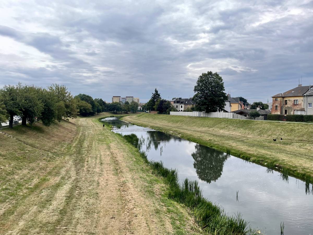 Řeka Opava ve stejnojmenném městě rok po povodních teče poklidně, mnoho metrů pod úrovní svahu.
