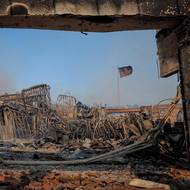 Americká vlajka vlaje mezi troskami spálených budov v čtvrti Pacific Palisades. (Los Angeles, 8. ledna)