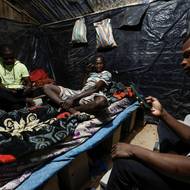 Diallo pracuje 15 dní v kuse na stavbě na okraji Nouakchottu. Přes den spí spolu s dalšími třemi muži v dřevěné chýši s plechovou střechou na postelích z cihel, které vyrábějí v noci, aby se vyhnuli dusivému horku. (Moktar Diallo, Garry Ndajy a Samuel Dembele se dívají do svých mobilních telefonů uvnitř chatrče, kde všichni žijí během pracovních dní, na okraji Nouakchottu v Mauritánii, 24. února.)