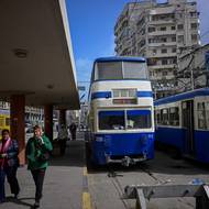 Linka s dvoupatrovými modrými vozy byla zprovozněna v době rozvoje kosmopolitní metropole, která tehdy hostila významnou evropskou komunitu. V Alexandrii je jeden z mála tramvajových systémů na světě, který používá dvoupatrové vozy – dalšími příklady jsou anglický Blackpool a Hongkong. (Cestující kráčejí po nástupišti tramvajové zastávky v Alexandrii, 18. února 2026.)