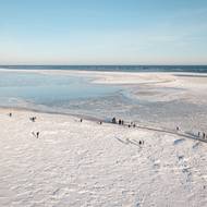 Voda zmrzla i v části zálivu. Na snímku se prochází lidé po pláži pokryté ledem vyvrženým vlnami ve vesnici Mikoszewo, která leží u ústí Visly, 31. ledna.