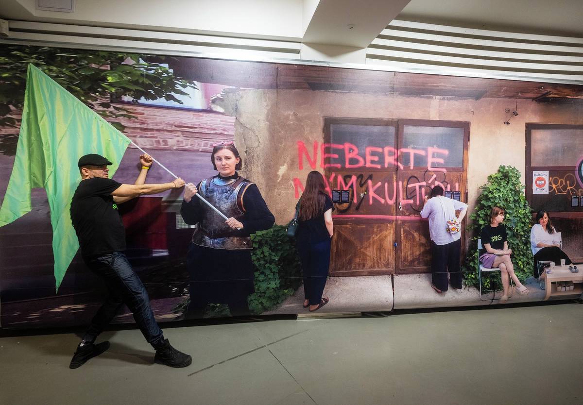 Na fotografii z výstavy Slobodná národná galéria – Popis jedného zápasu, kterou lze v pražském Domě fotografie vidět do 29. března, kurátor Braňo Matis pózuje před fotografií vzkazu na garáži Slovenské národní galerie.