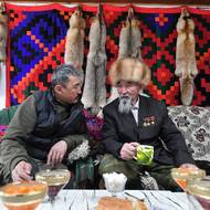 Akmatovovi ve svém domě. Stěny obývacího pokoje zdobí řada vlčích kožešin. Nejstarší Taštanbek má na saku připnutá dvě sovětská vyznamenání „Hrdina socialistické práce“, která si vysloužil za své chovatelské úsilí. 