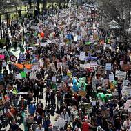 Demonstranti nesou transparenty při pochodu po Naito Parkway 