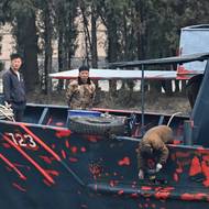 Severokorejští muži pracují na lodi na břehu řeky Jalu, město Sinuidžu, 24. března.