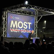 Péter Magyar na pódiu v Gödu pronesl kritický a mobilizační projev. Za Magyarem je patrný areál továrny.