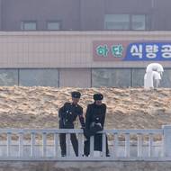 Severokorejští pohraničníci stojí na nově zbudovaném nábřeží ve městě Sinuidžu v Severní Koreji. Vyfoceno 15. ledna z čínského Tan-tungu.