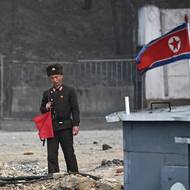 Voják stojí na stráži vedle člunů na břehu řeky Jalu v severokorejském Sinuidžu, 24. března. 