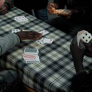 Súdánští migranti hrají karty v táboře Ecluse naproti Stade de France. 12. listopadu 2020 v Saint-Denis.