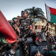 Podobně jako při povstáních Gen Z v Bangladéši, Nepálu či Bulharsku donutila madagaskarská mládež ke změně režimu, ale byla vyloučena z utváření následného politického přechodu. (Demonstranti jásají a mávají vlajkami před radnicí v Antananarivu. 11. října 2025.)