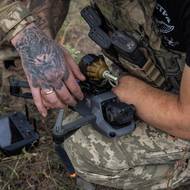 Tyto vývojové trendy vyvolaly neúprosný závod ve zbrojení v oblasti dronů a proměnily rozsáhlé oblasti Ukrajiny v „zóny smrti“. Civilisté se stávají terčem útoků a jsou nuceni opouštět své domovy, zatímco vojáci tráví většinu času v podzemních bunkrech nebo sklepech, odkud není možné zajistit zásobování ani evakuaci zraněných. Tato reportáž dokumentuje snahy Ukrajiny o posílení svých dronových kapacit a dopady ruských dronových útoků na civilisty.

(Ukrajinský voják drží svou částečně amputovanou rukou dron, na který se právě montuje granát. V roce 2022 muž utrpěl zranění a nyní cvičí rekruty v ovládání dronů. Vyfoceno v Doněcké oblasti, 5. srpna 2024.)